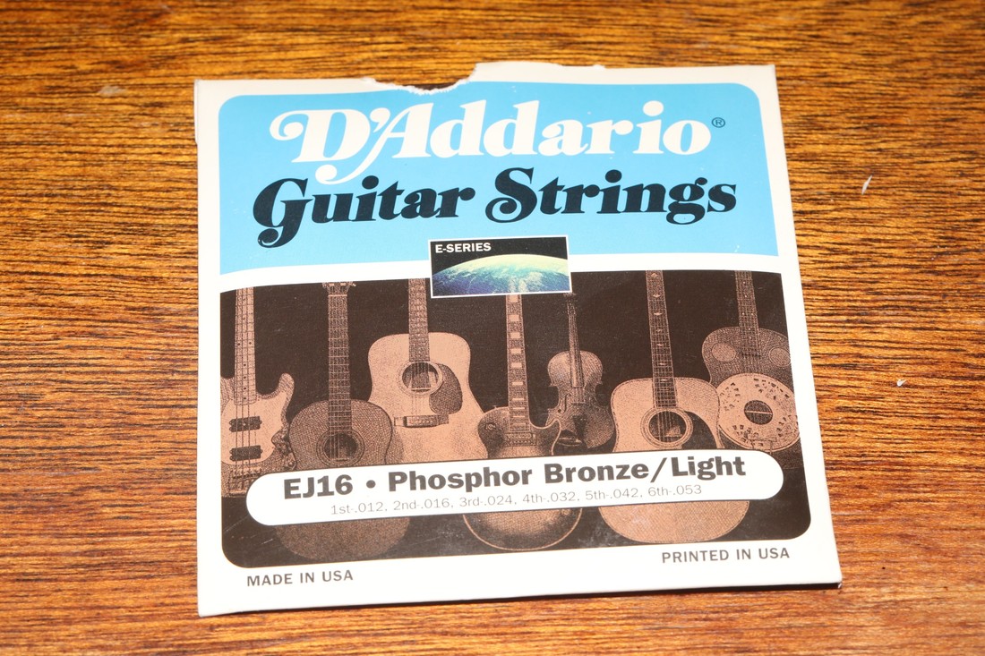 D'Addario phosphor-bronze acoustic guitar strings photographed on a wooden surface.